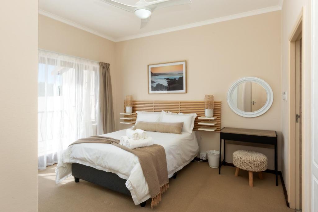 a bedroom with a large bed and a mirror at Stay@Tuscany - 3 Bedroom Luxury Holiday Home in Mossel Bay