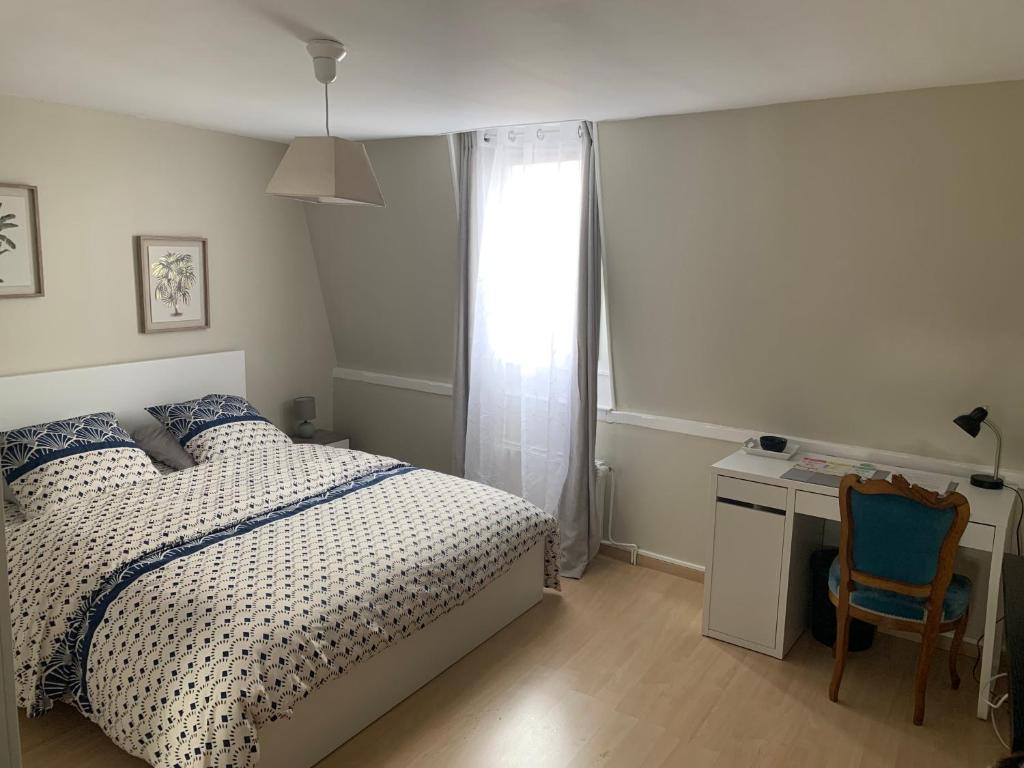 1 dormitorio con cama, escritorio y ventana en chambre cosy, en Annappes