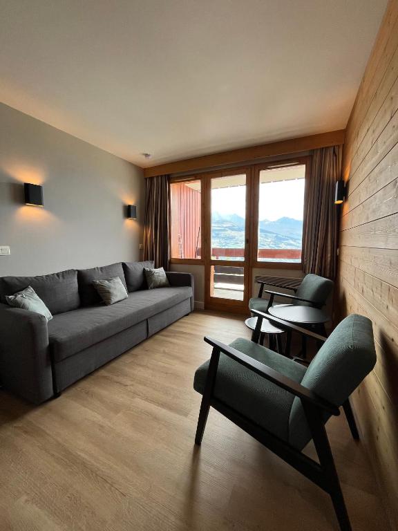 un salon avec un canapé, des chaises et des fenêtres dans l'établissement Apartment Paradiski 309 - La Plagne - ski-in, ski-out, à La Plagne Tarentaise