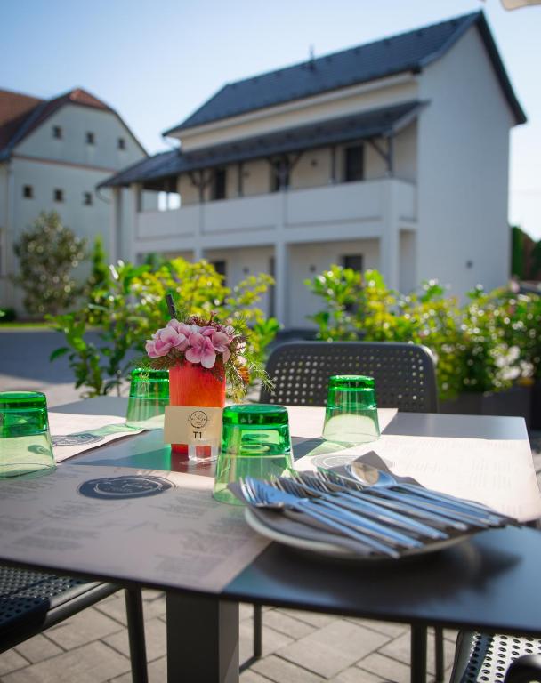 a table with a plate and a vase of flowers on it at La Róna Rooms in Kiskőrös