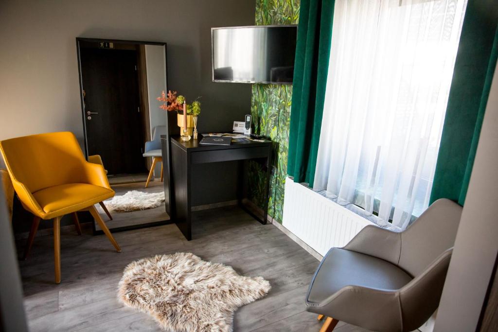 uma sala de estar com uma secretária, uma cadeira e uma mesa em La Róna Rooms em Kiskorös