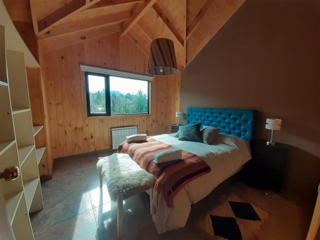 a bedroom with a bed with a blue headboard and a window at cabañas la arqueria candelaria in Villa Meliquina