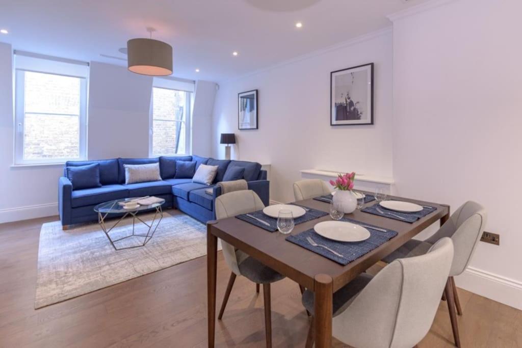 a living room with a table and a blue couch at Modern, Luxurious 1BR Flat- Heart of Covent Garden in London