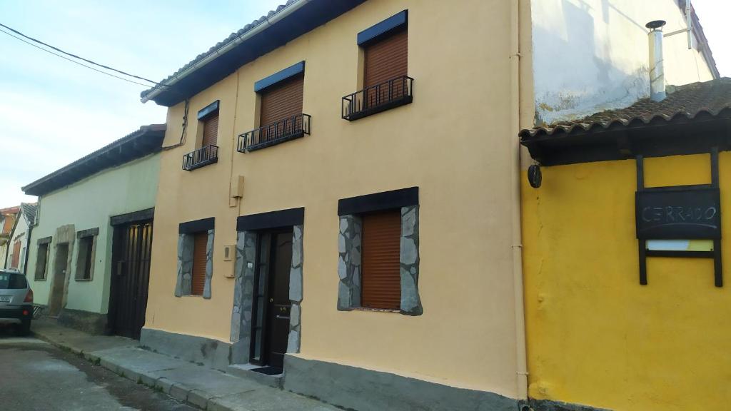 un edificio amarillo con ventanas y balcones en una calle en Casa Juan en Santa Olaja de Eslonza