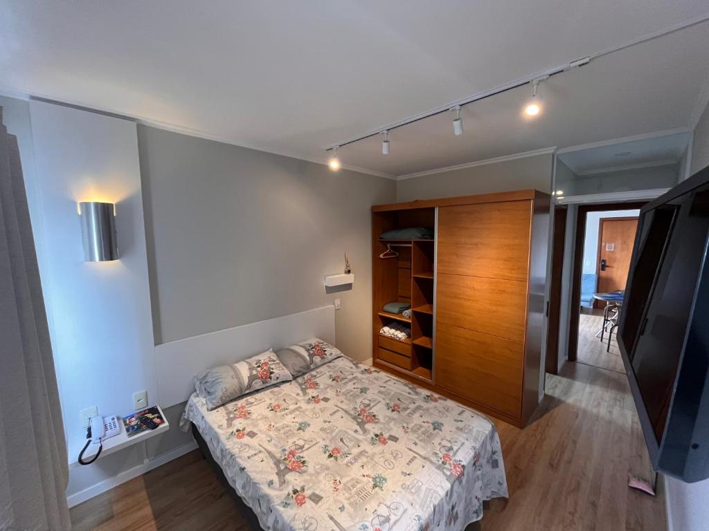 a small bedroom with a bed and a tv at Loft no centro de Joinville in Joinville