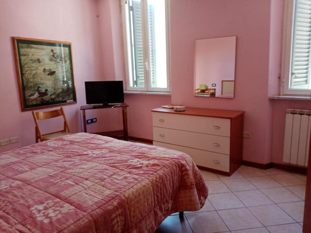 een slaapkamer met roze muren en een bed en een dressoir bij VIAREGGINA VIA PAOLINA in Viareggio