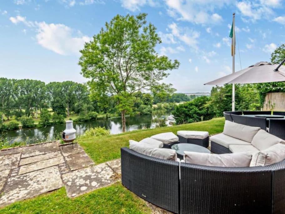 a backyard with a couch and an umbrella at Riverbank house - Cookham in Cookham