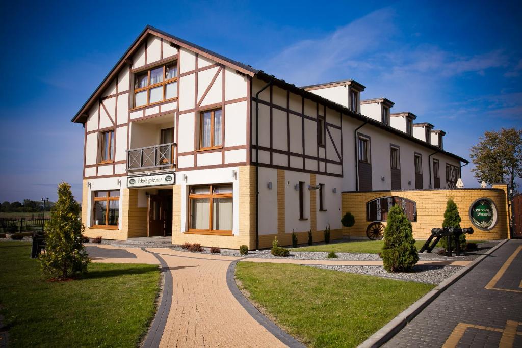 un grand bâtiment blanc avec un sentier devant lui dans l'établissement Cedrowy Dworek, à Cedry Wielkie