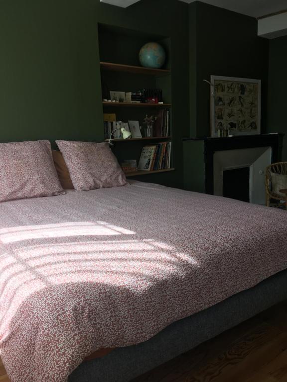 um quarto com uma cama com um cobertor rosa em Le bois de mon coeur - studio cosy indépendant 