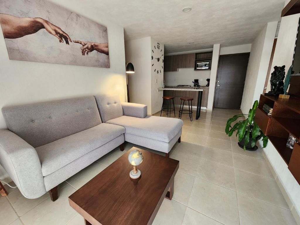 ein Wohnzimmer mit einem Sofa und einem Tisch in der Unterkunft Confortante departamento con Pkg Privado in Guadalajara