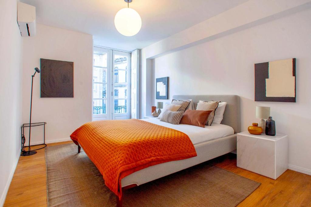 sypialnia z łóżkiem z pomarańczowym kocem w obiekcie Porto Downtown Flats w Porto