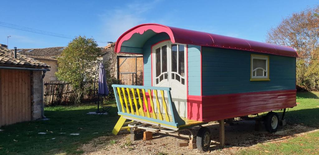 a colorful play house sitting in a yard at Roulotte Framboise in Vaux-en Couhé