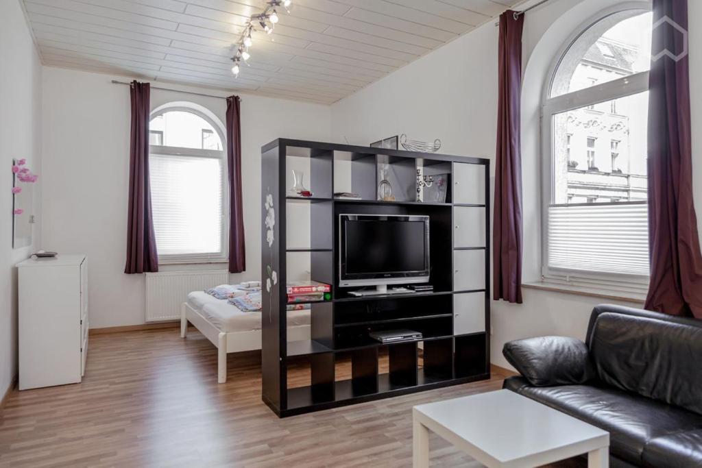 ein Wohnzimmer mit einem Sofa und einem TV in der Unterkunft StayINN Lindenau in Leipzig