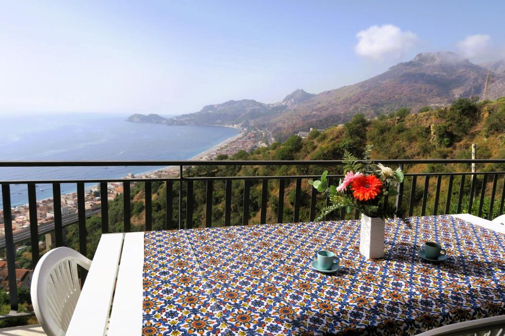 a table on a balcony with a view of the ocean at Collina del Sole in Letojanni