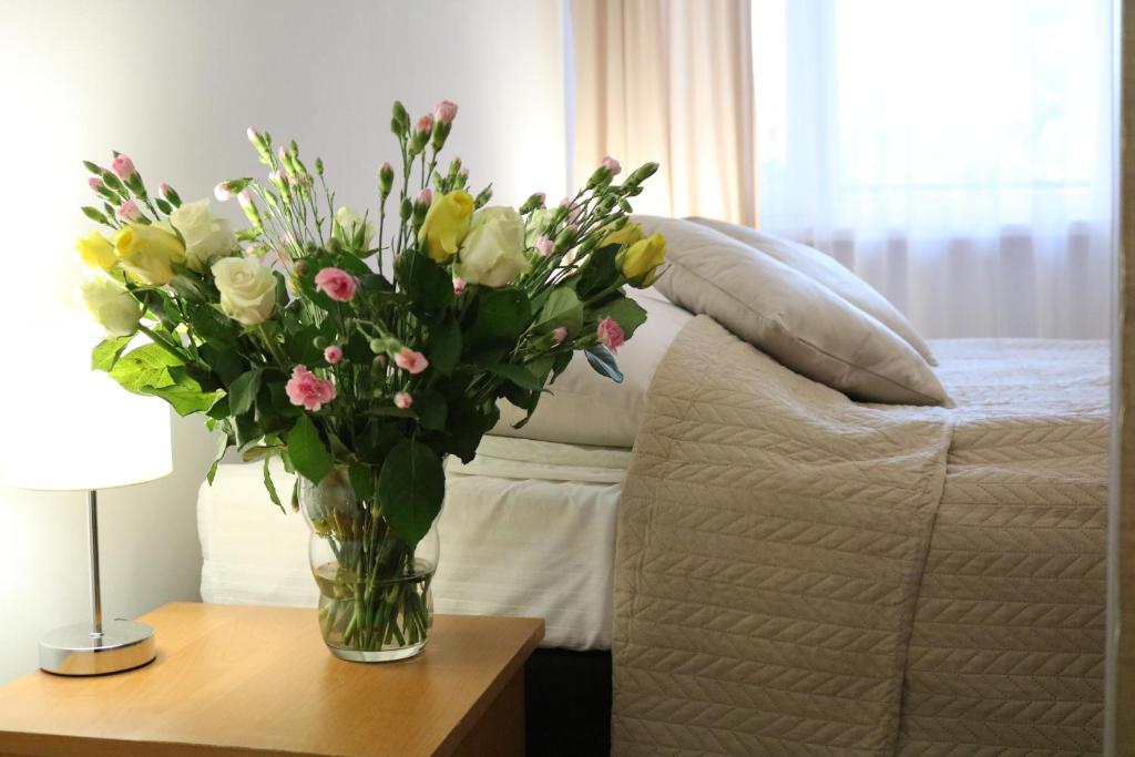 a vase of flowers on a table next to a bed at Dom Gościnny Posejdon in Pobierowo