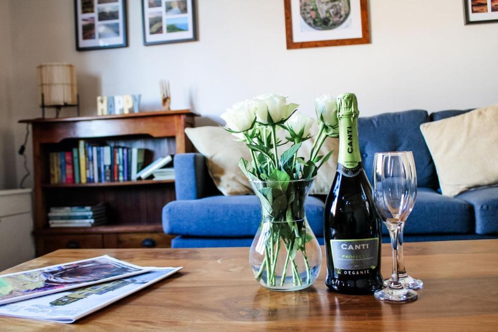 een fles wijn en een vaas met bloemen op een tafel bij The Brown Box Holiday Let in Loftus