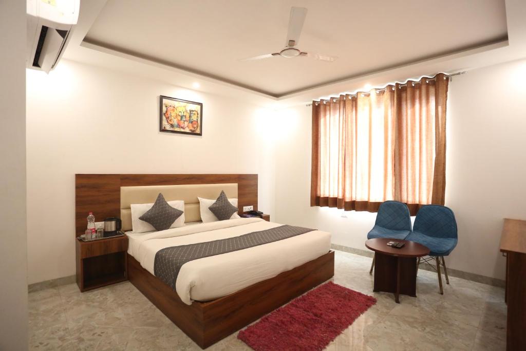 a bedroom with a bed and two blue chairs at Hotel De Clark Residency Delhi Airport in New Delhi