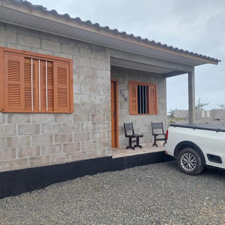 un coche aparcado fuera de una casa de ladrillo con un coche aparcado fuera en Casa para temporada em Arroio do Silva a 900m do mar, en Arroio do Silva