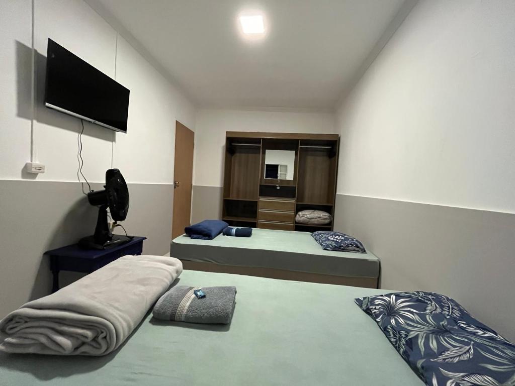a bedroom with two beds and a flat screen tv at Toca do Tatu in Itu