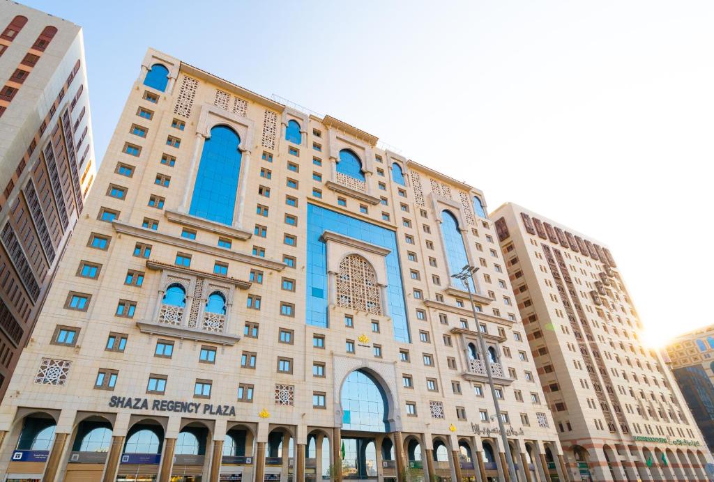 Shaza Regency Plaza Al Madinah في المدينة المنورة: مبنى كبير مع نوافذ زرقاء في مدينة