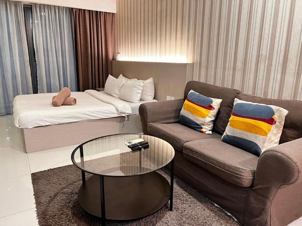 een woonkamer met een bank en een bed bij Mercu Summer Suites KLCC By Minutepointhome in Kuala Lumpur