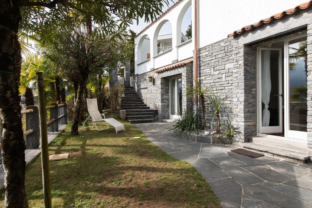 a yard with a chair in front of a house at Villa Ani in Ascona