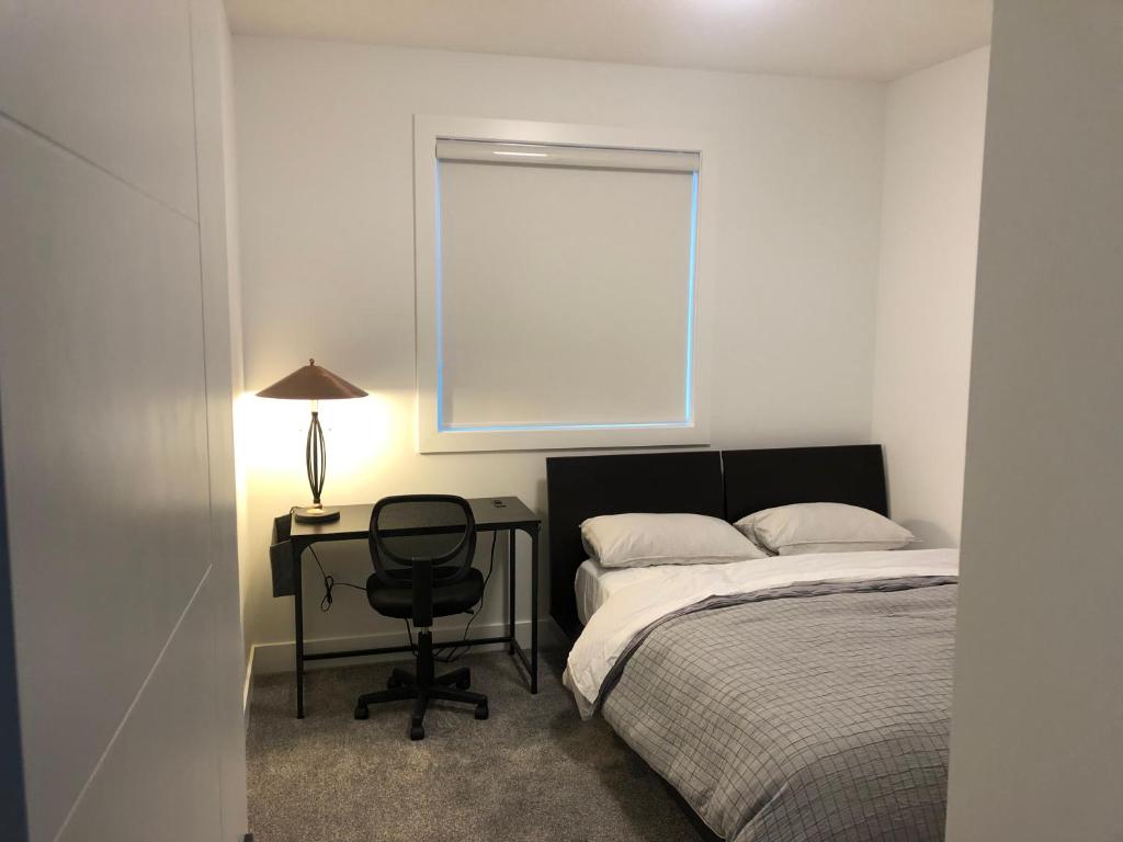 1 dormitorio con cama, escritorio y ventana en Southpointe_Homestay, en Fort Saskatchewan