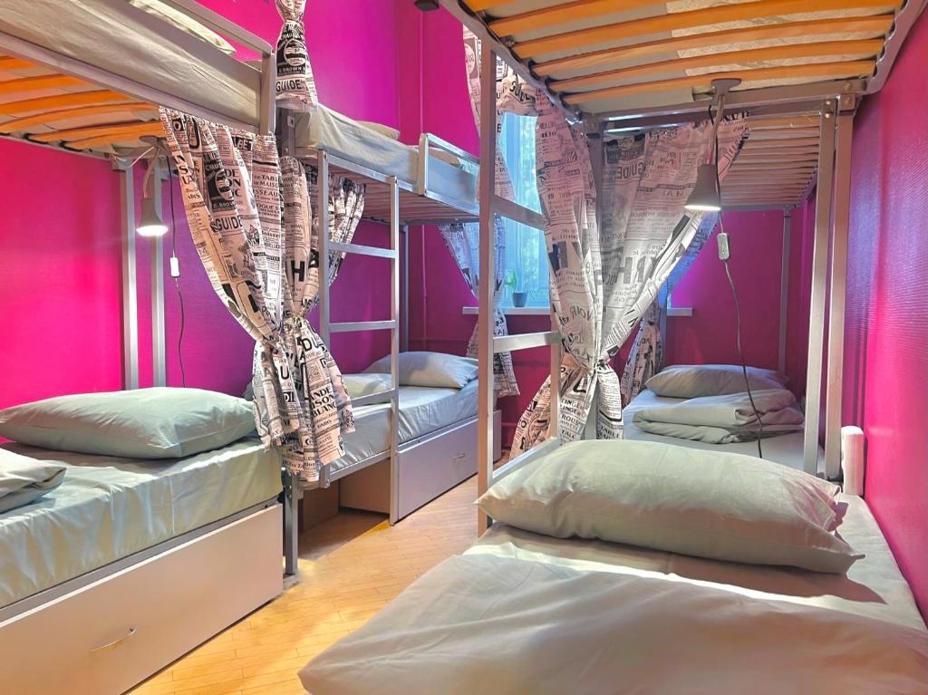 a room with three bunk beds with pink walls at Pechersky Hostel in Kyiv