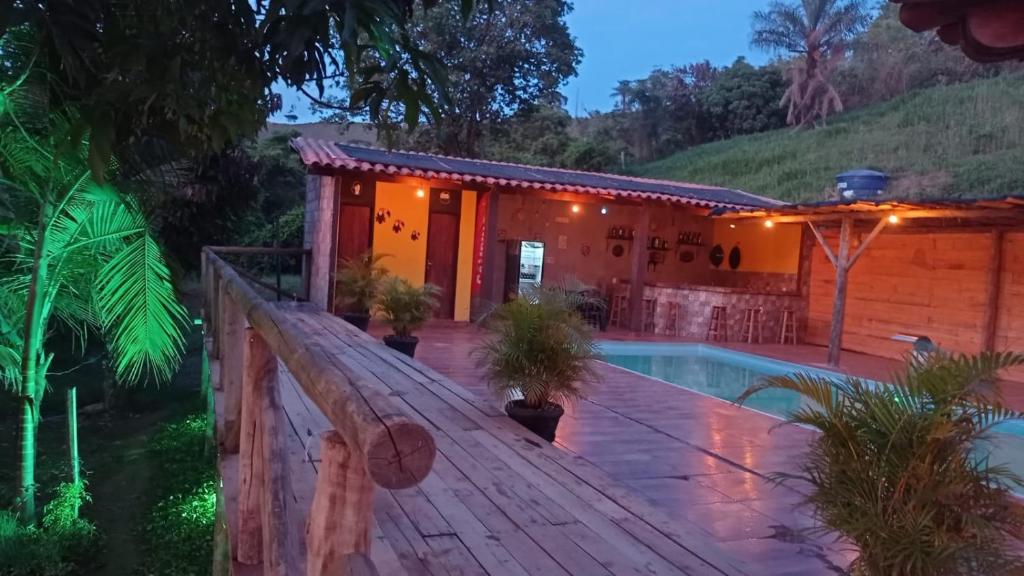 a house with a wooden deck and a swimming pool at Pousada e camping Canastra Mineira in São Roque de Minas