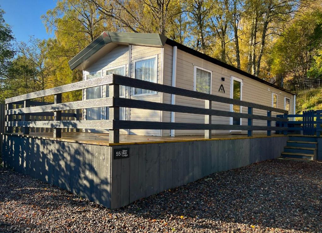 ein Haus mit einem Zaun an der Seite in der Unterkunft Silver Birch Lodge Aviemore in Aviemore