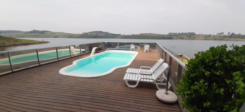 a swimming pool on a deck with a view of the water at casa nas marinas boa vista in Boa Vista Parecida