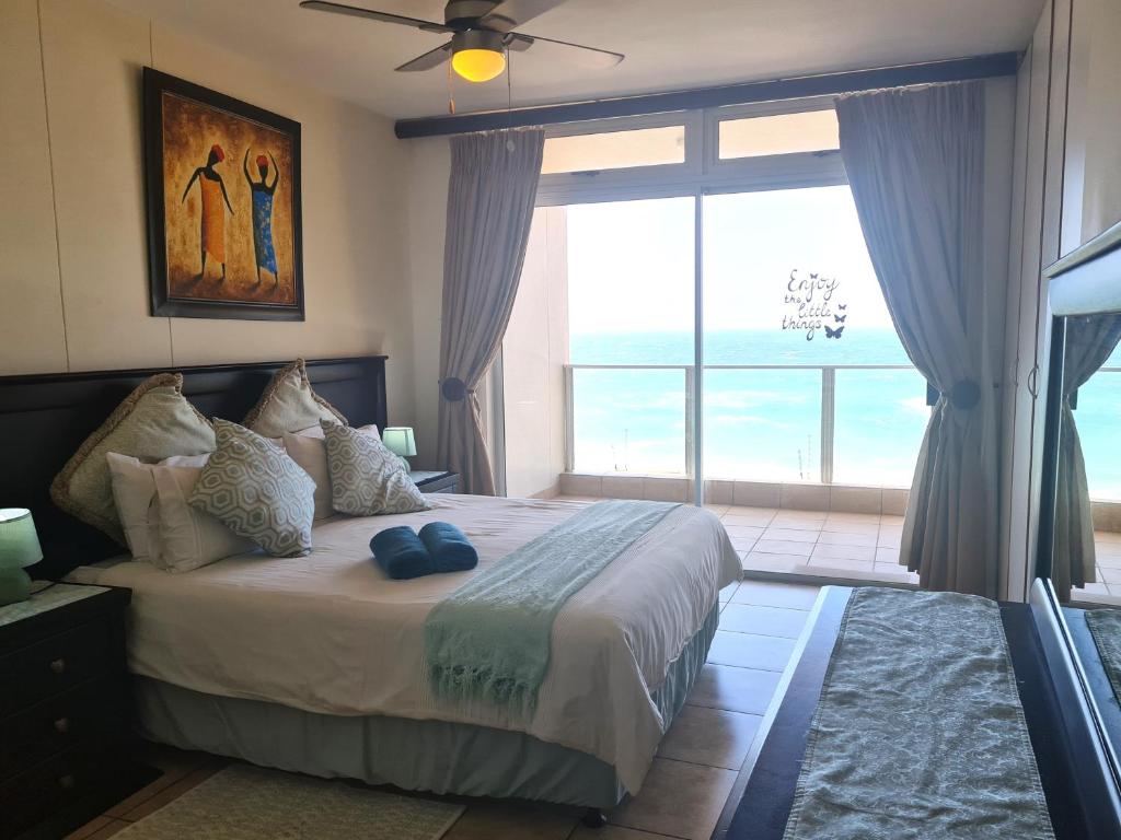 a bedroom with a large bed with a large window at Santorini 105A in Margate