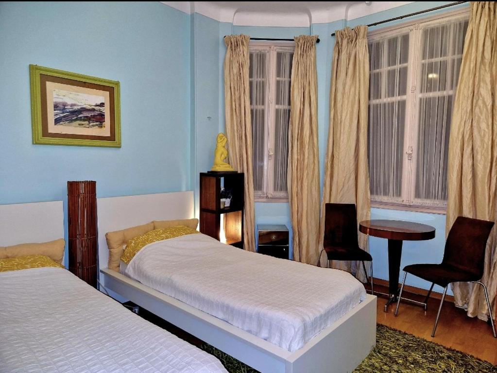 a bedroom with two beds and a table and windows at Home for 2 few steps from casino monte carlo and beach in Beausoleil