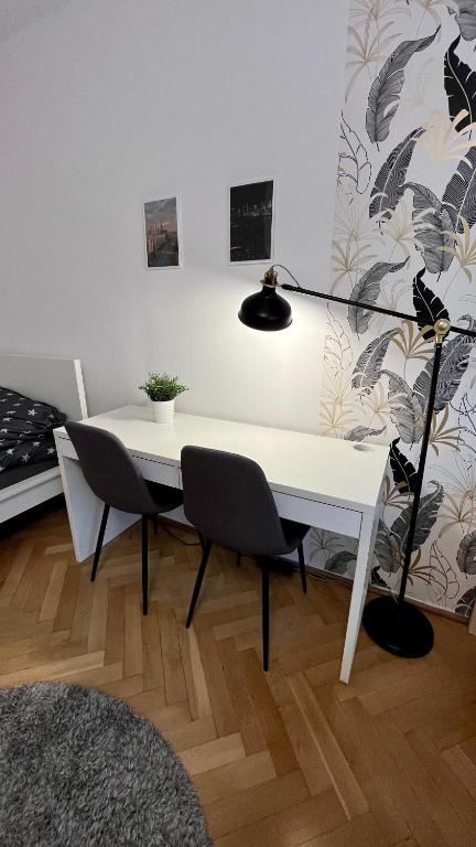 a white desk with two chairs and a lamp at Warszawa Krucza Pokoje in Warsaw