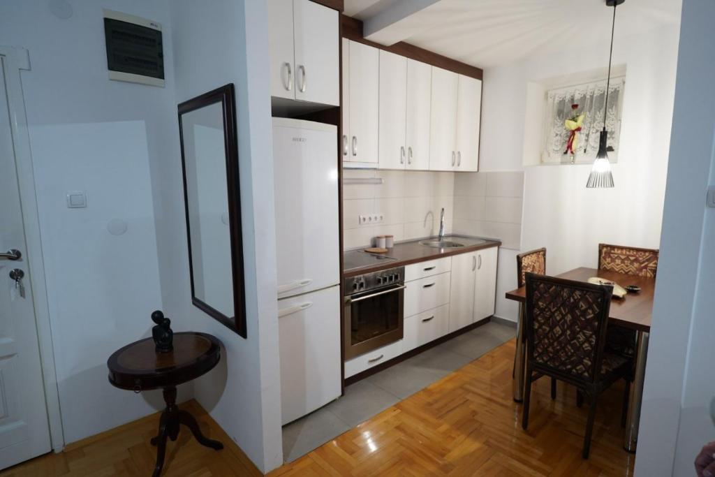 una cocina con armarios blancos, una mesa pequeña y una sidra de mesa en Stan na dan Paracin 035, en Paraćin