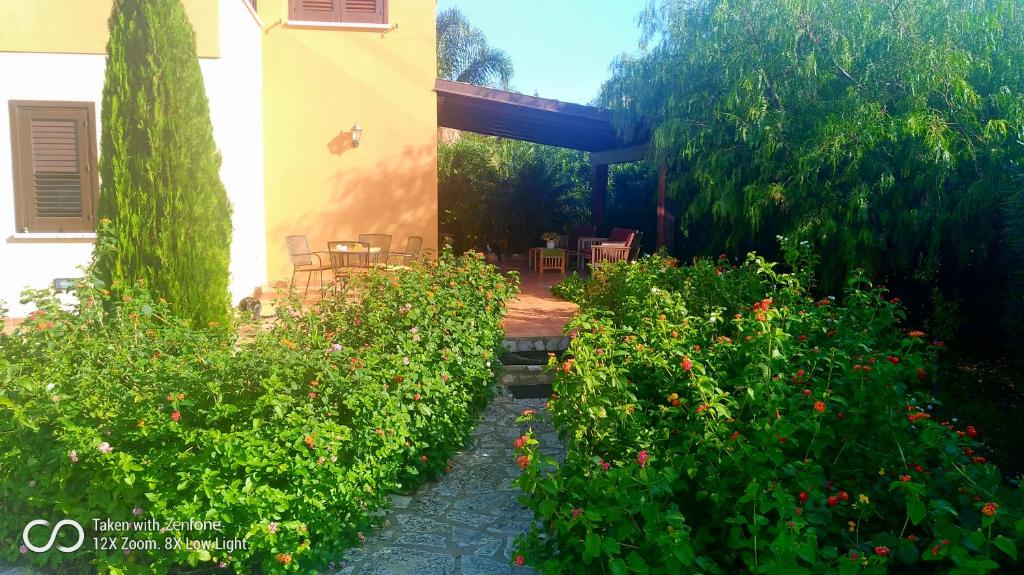 un jardín con una casa y algunos arbustos y flores en ViViHolidays, en Castellammare del Golfo
