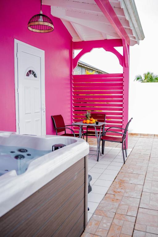 Habitación rosa con mesa y sillas en el patio en Domaine de la rosa spa privatif en Les Abymes
