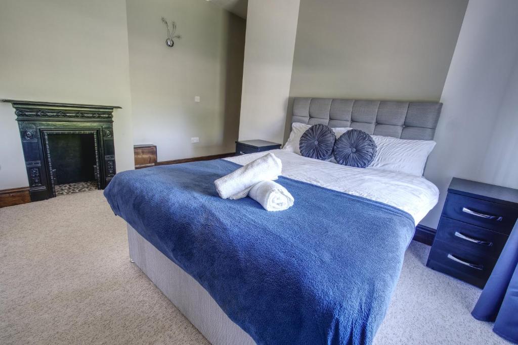 ein Schlafzimmer mit einem großen Bett mit blauer Bettwäsche und Kissen in der Unterkunft #2 Dunkirk by DerBnB, Modern 2 Bedroom City Centre Apartment, Free Parking, WI-FI, Netflix & Within Walking Distance of the City Centre in Derby