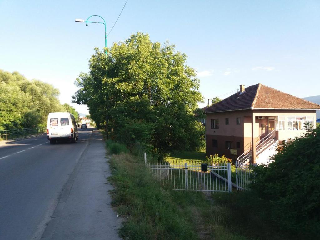 Ein Van fährt eine Straße entlang neben einem Haus in der Unterkunft Apartman na vikendici in Sarajevo