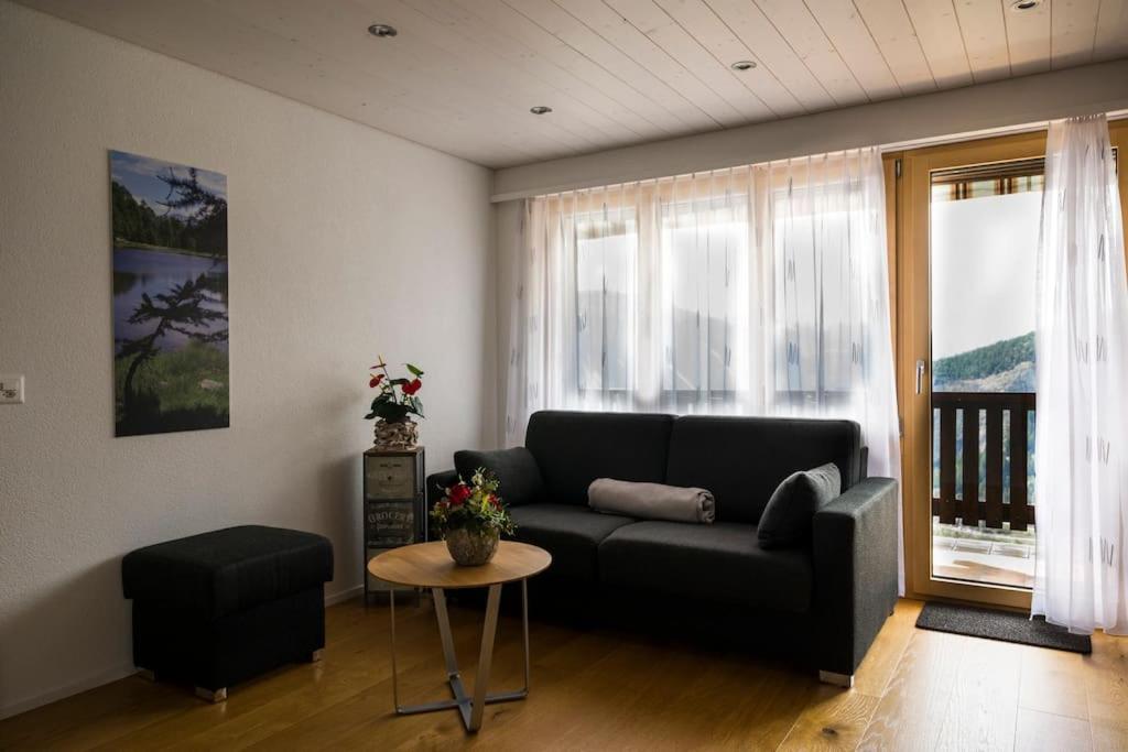 a living room with a black couch and a table at Moderne 2-Zimmer-Wohnung in Albinen mit Aussicht in Albinen