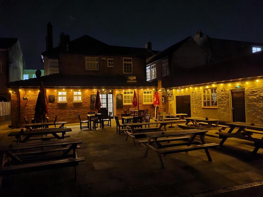 a group of picnic tables in front of a building with lights at The Gillygate Bar and Rooms in York