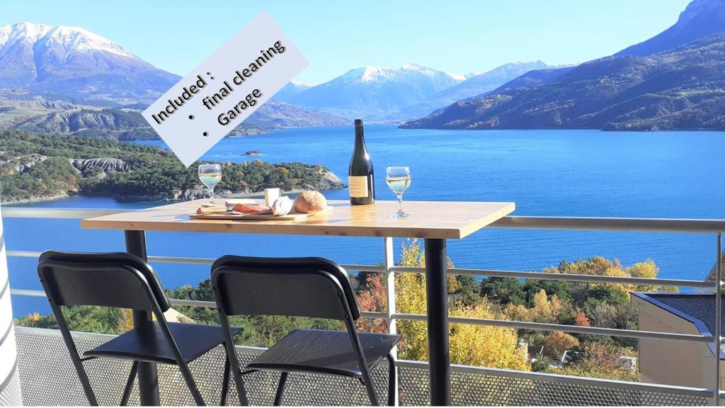 a table with a bottle of wine and glasses on a balcony at Vaste appartement 3 chambres - Vue exceptionnelle in Chorges