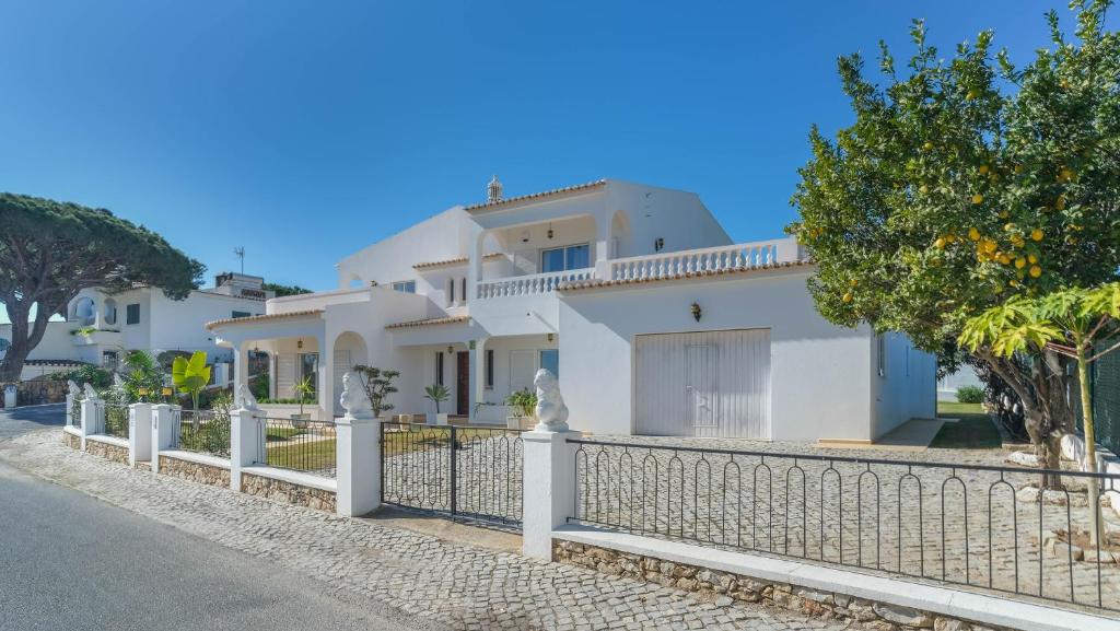 een wit huis met een hek ervoor bij Casa SP- Villa with heated pool near Vilamoura, Vale do Lobo in Quarteira
