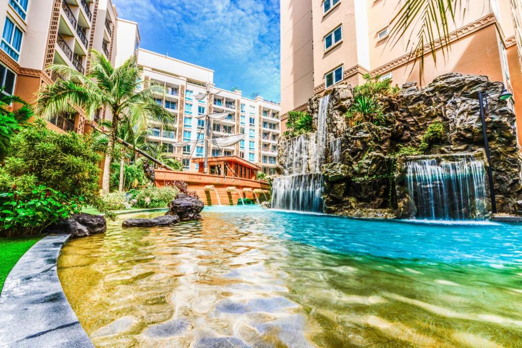 una piscina en un hotel con una cascada y edificios en Atlantis Condo Resort Pattaya, en Jomtien Beach