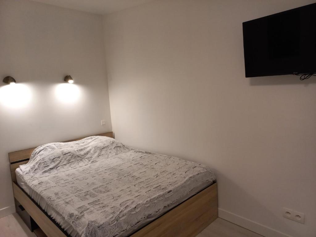 um pequeno quarto com uma cama e uma televisão de ecrã plano em Studio tt confort neuf et équipé em Noyon