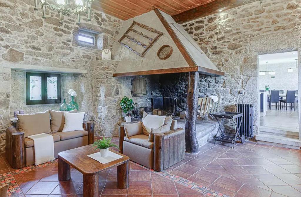 a living room with couches and a stone wall at Villamia in Coirós