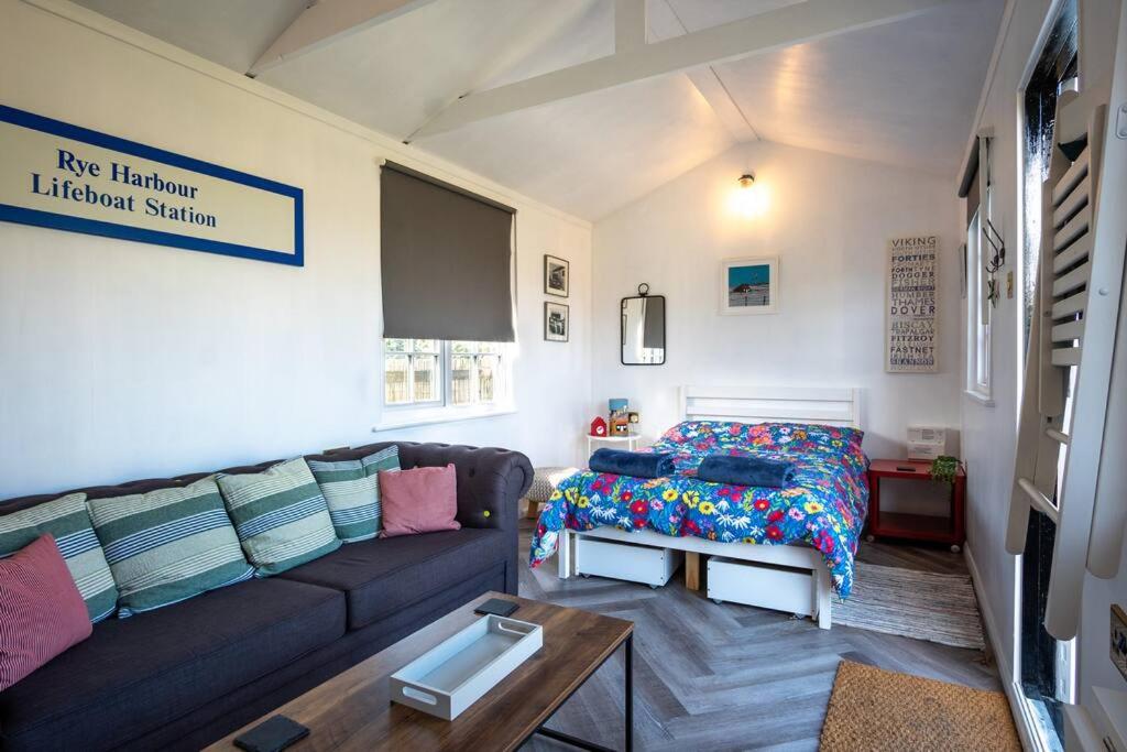 a living room with a couch and a bed at The Other Red Hut in Rye Harbour