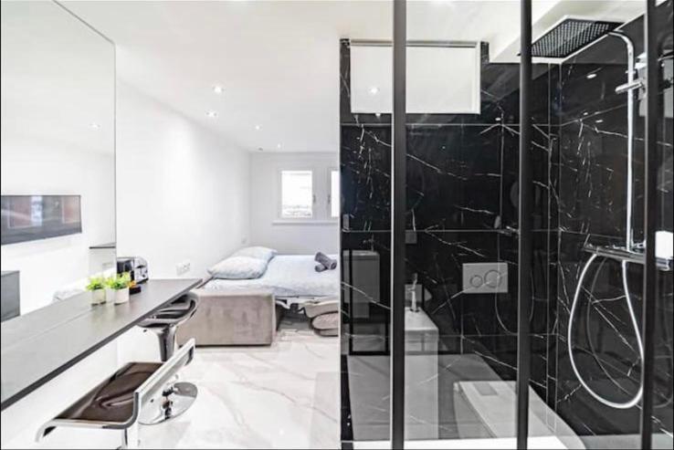 a bathroom with a glass shower and a bed at Studio chaleureux tête d'or in Lyon