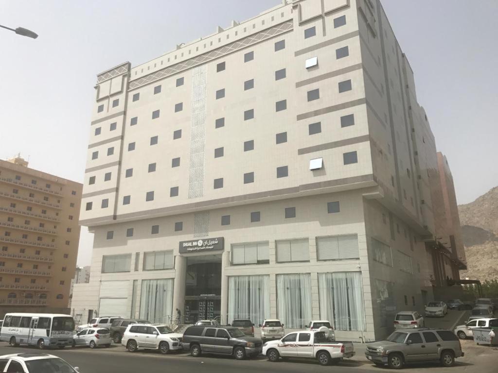 un gran edificio blanco con coches estacionados frente a él en Shouel Inn Furnished Apartments, en La Meca