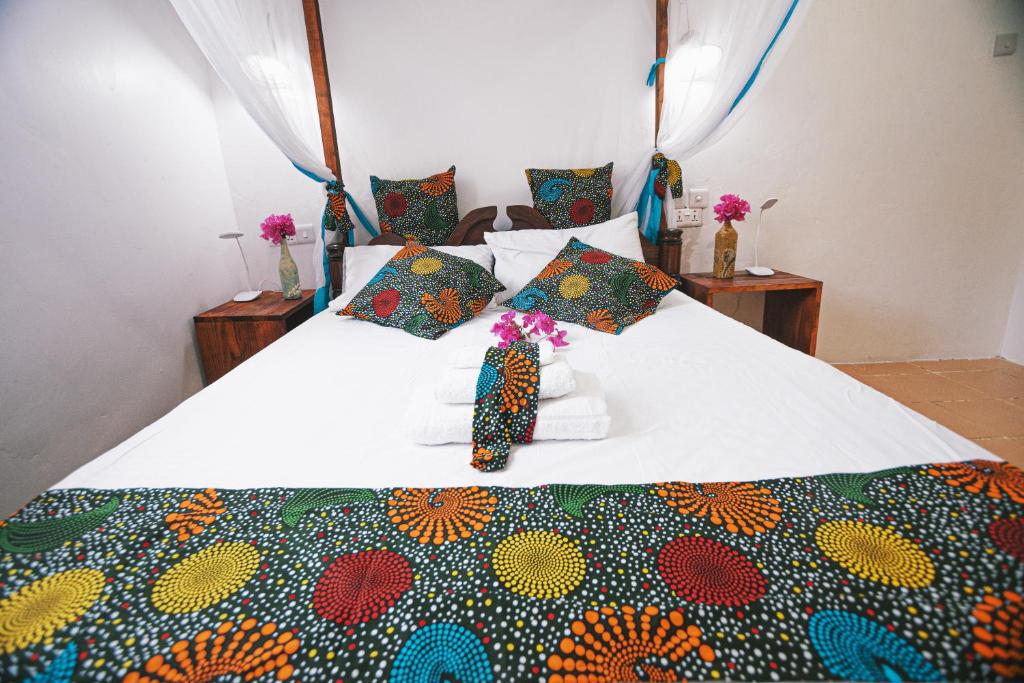 a bed with a colorful blanket on it with flowers on it at Cozy Lodge - Guesthouse in Jambiani